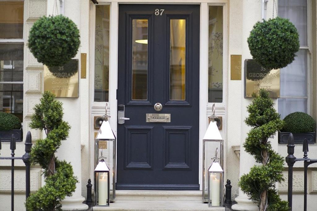 uma porta azul da frente de uma casa branca com plantas em Georgian House Hotel em Londres