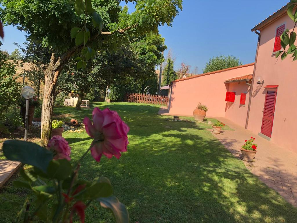 a yard with a pink building and a pink flower at Casa Laura in Cortona