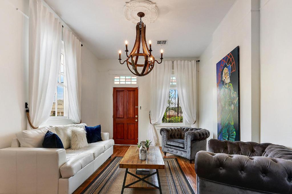 a living room with a white couch and a chandelier at Modern Victorian House With Relaxing Courtyard in New Orleans