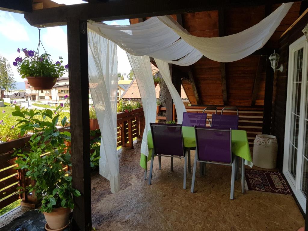 un patio con mesa y sillas en un porche en Enjoy the Silence Holiday Home, en Vlašić