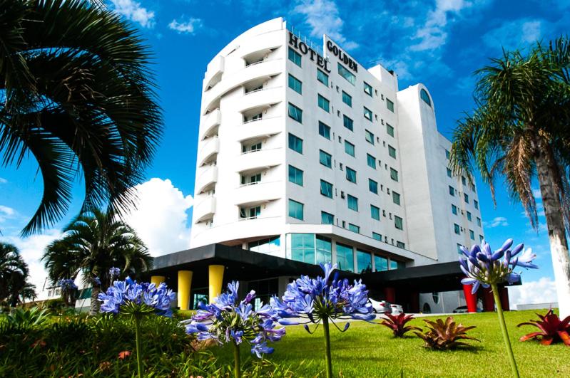 a hotel with purple flowers in front of a building at Favorita Golden Hotel e Eventos in São José