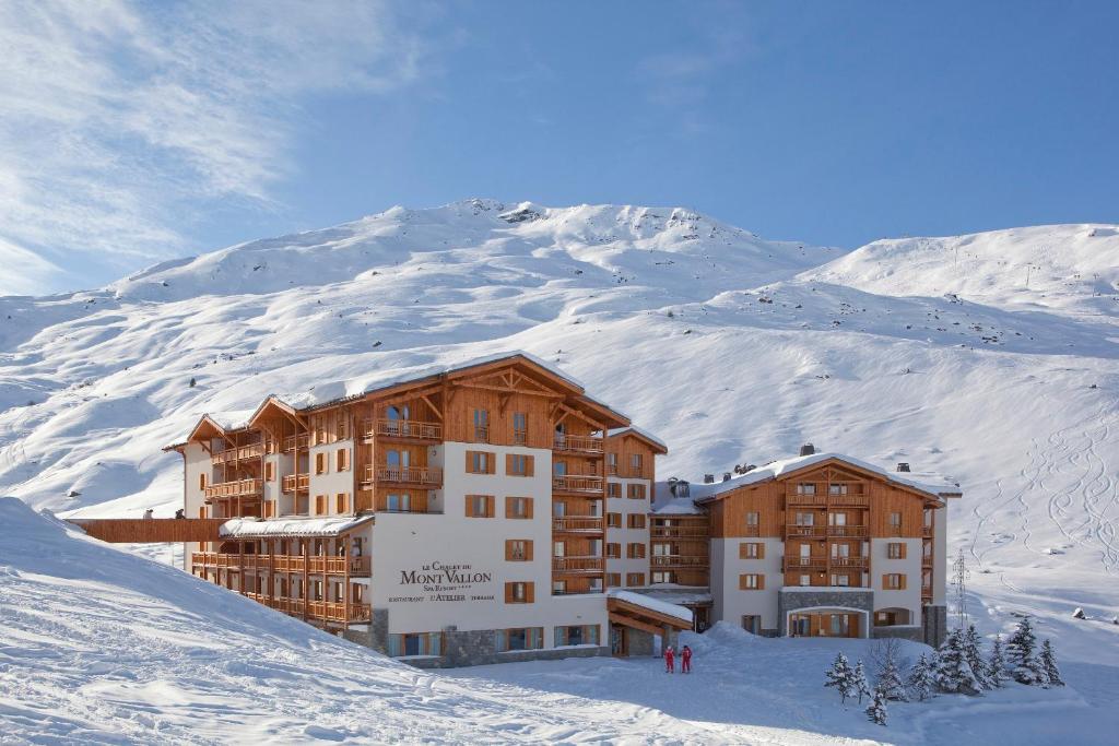 un grand bâtiment dans la neige sur une montagne dans l'établissement Le Chalet du Mont Vallon Spa Resort, aux Menuires