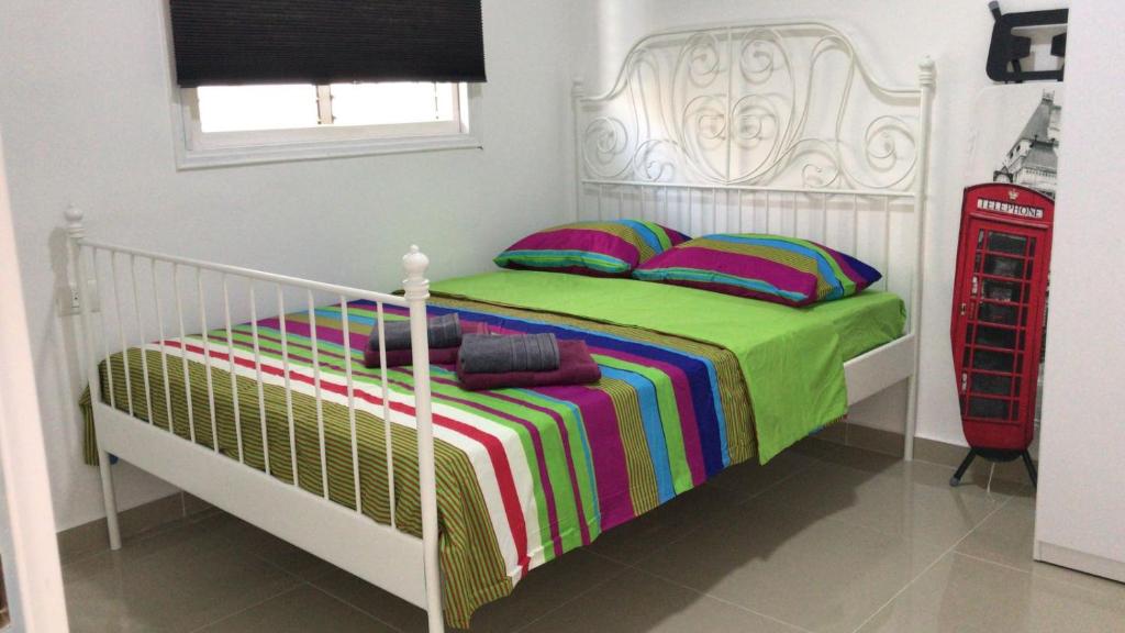 - une chambre avec un lit blanc et une couverture colorée dans l'établissement Isramax apartment near the beach., à Bat Yam