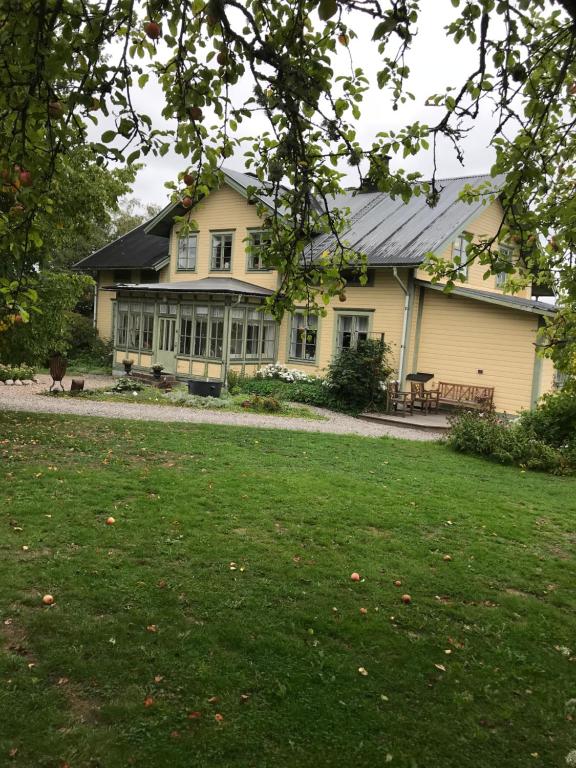 une grande maison avec une pelouse devant elle dans l'établissement Perssons Magasin, à Västra Löa