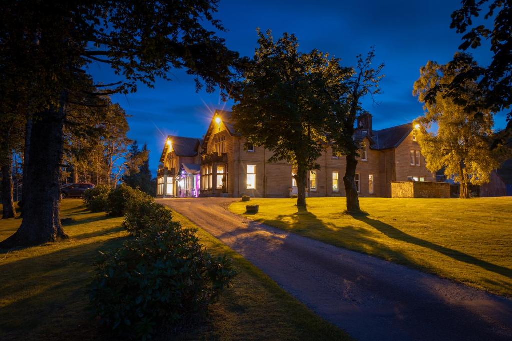 una finca de noche con árboles delante de ella en Ledgowan Lodge Hotel, en Achnasheen