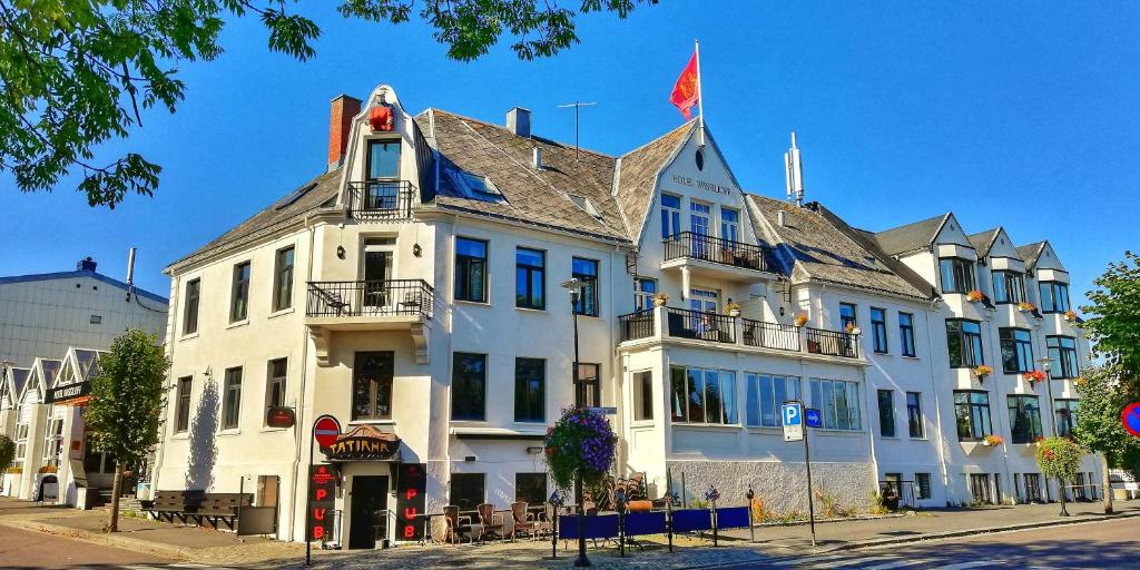 a white building with a flag on top of it at Hotel Wassilioff - Unike Hoteller in Stavern