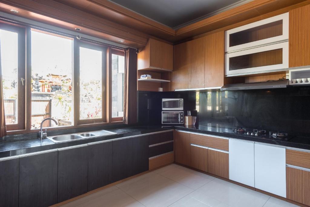 a kitchen with wooden cabinets and a large window at Villa Melasti Wardana in Uluwatu