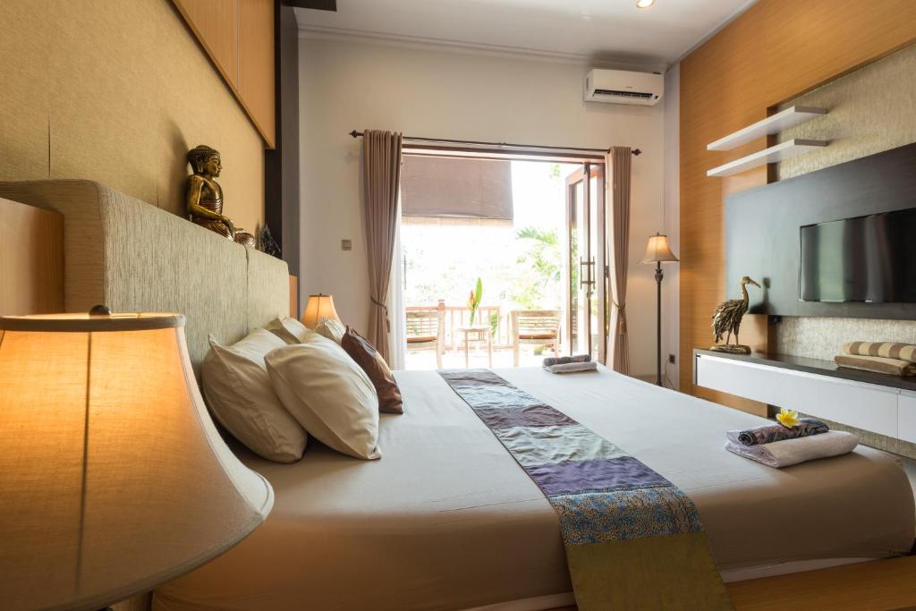 a bedroom with a bed with a television and a window at Villa Melasti Wardana in Uluwatu