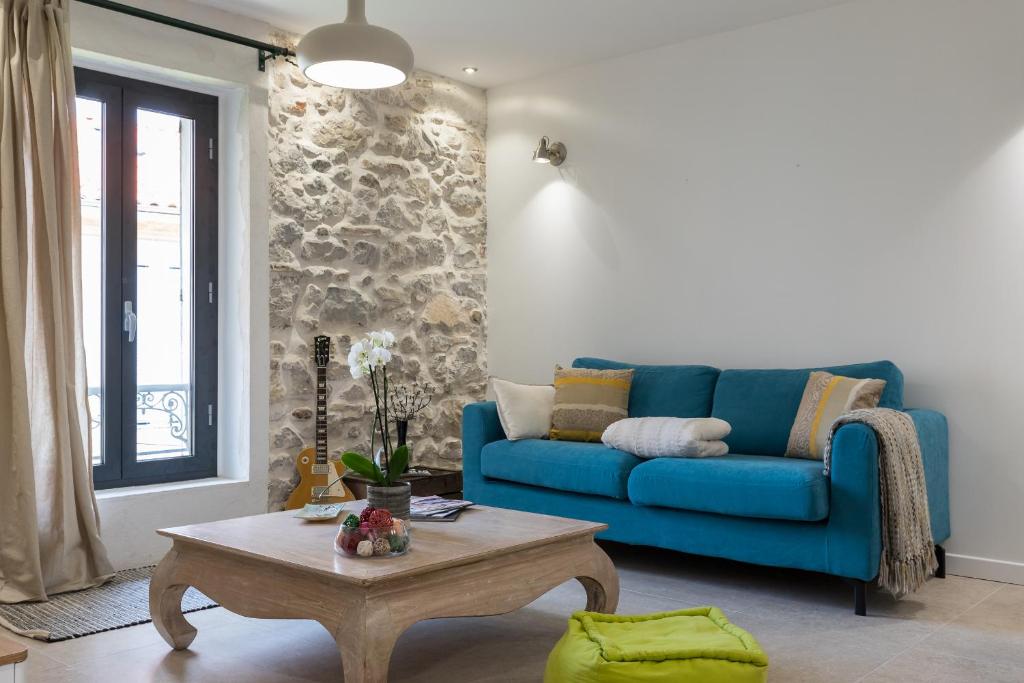 un salon avec un canapé bleu et une table basse dans l'établissement Migrainier côté cour, à Antibes