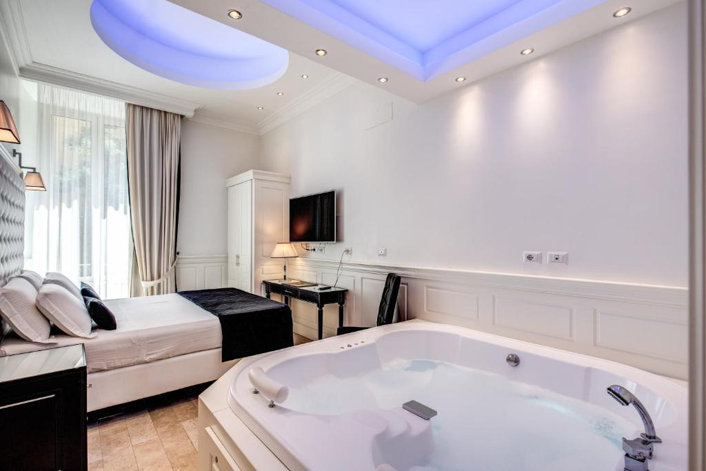 a bathroom with a large bath tub and a bed at Hotel dei Quiriti Suite in Rome