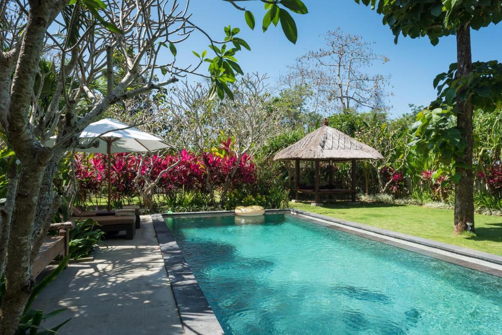 a swimming pool in a garden with a gazebo at Villa Melasti Wardana in Uluwatu