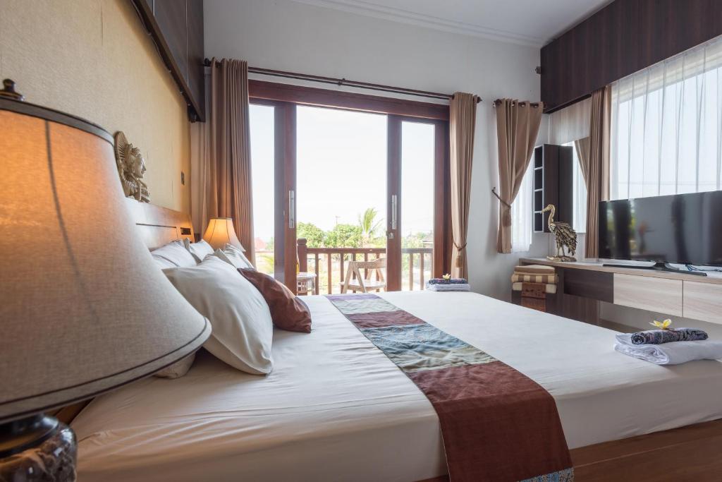 a bedroom with a large bed with a large window at Villa Melasti Wardana in Uluwatu