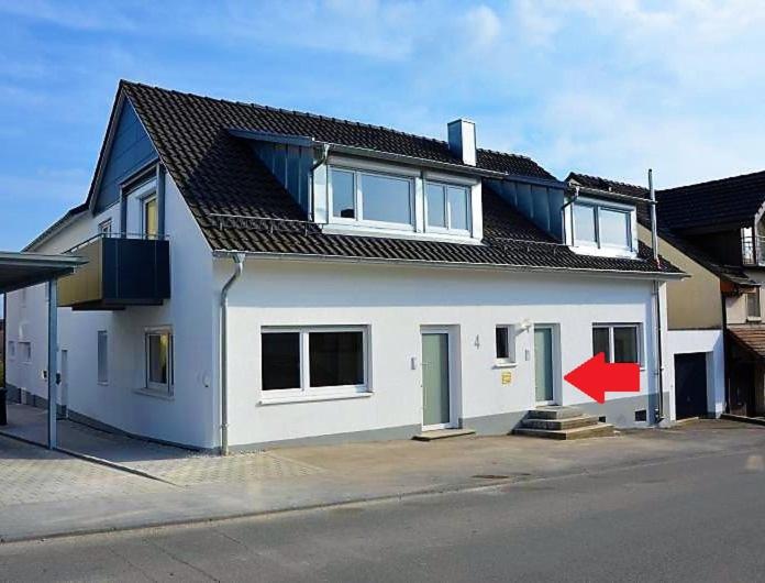 una casa blanca con una flecha roja delante de ella en BodenSEE Apartment Allensbach FEWO 2, en Allensbach