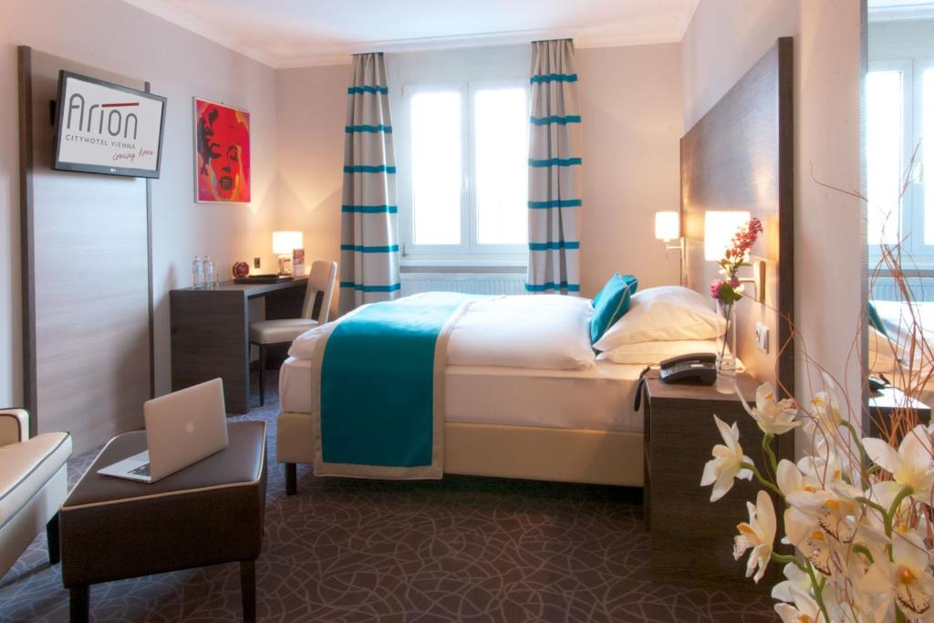 a hotel room with a bed and a desk with a laptop at Arion Cityhotel Vienna und Appartements in Vienna