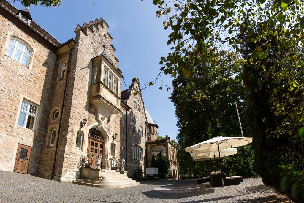 un edificio con una sombrilla delante de él en Schlosshotel Villa Westerberge, en Aschersleben