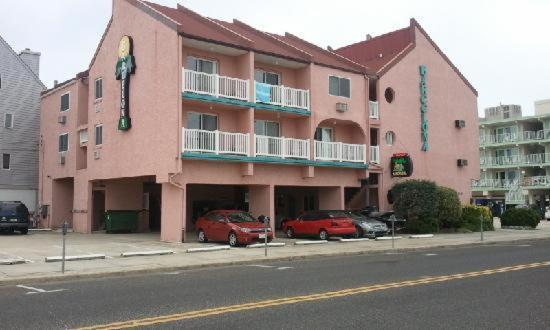 um edifício rosa com carros estacionados em frente em Barcelona Motel em Wildwood Crest