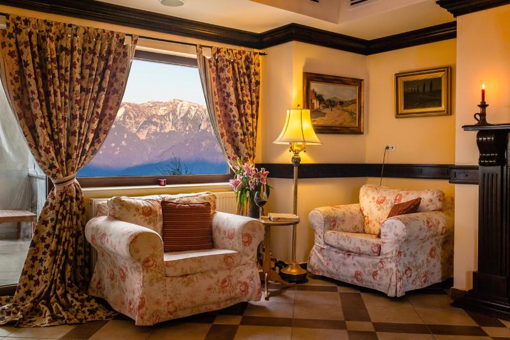 ein Wohnzimmer mit 2 Stühlen und einem Fenster in der Unterkunft Nobillis - Carpathian Residence in Peştera