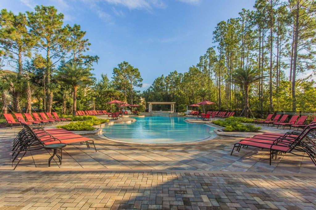a pool with chairs, tables and umbrellas in it at The Fountains Resort Orlando at ChampionsGate in Kissimmee