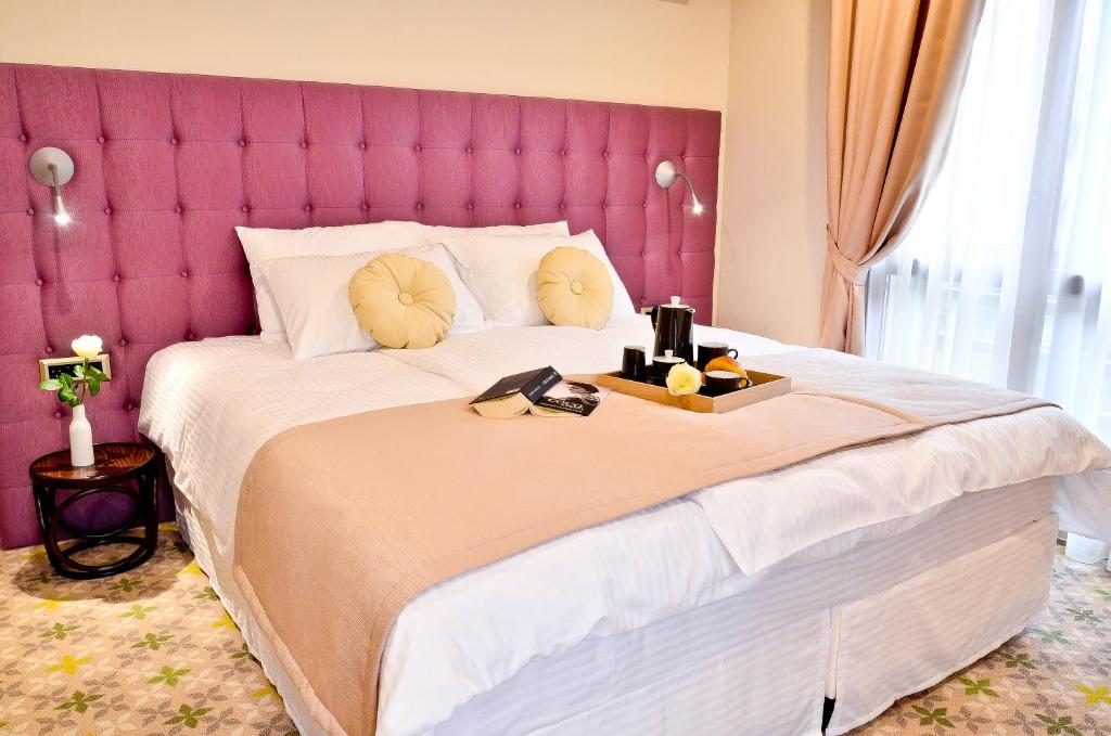 Schlafzimmer mit einem großen Bett mit einem rosa Kopfteil in der Unterkunft Hotel Capitolina City Chic in Cluj-Napoca
