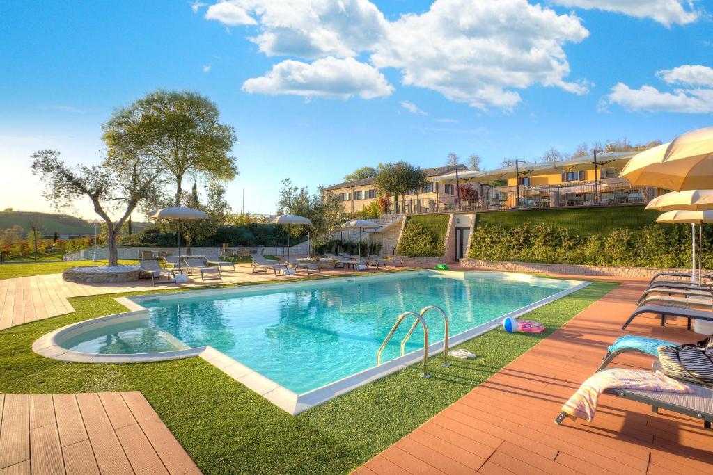 una piscina en un patio con sillas y sombrillas en Villa Gens Camuria en Camerano