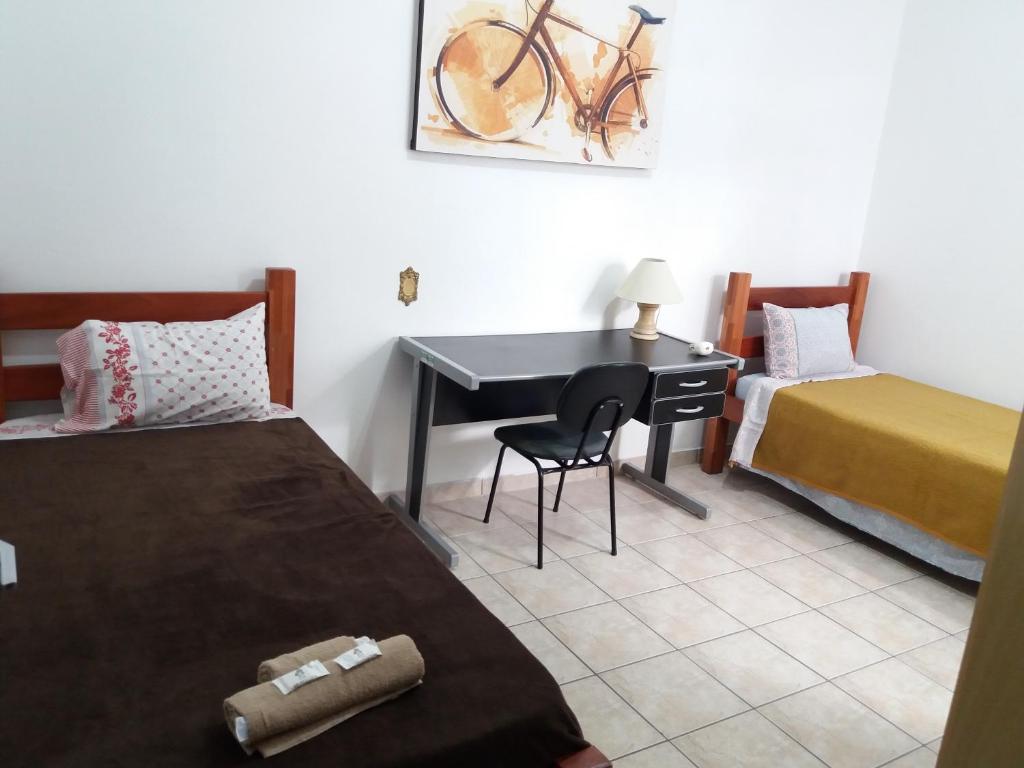 1 Schlafzimmer mit 2 Betten und einem Schreibtisch mit einem Stuhl in der Unterkunft Residencial Castelo Branco II in Campinas