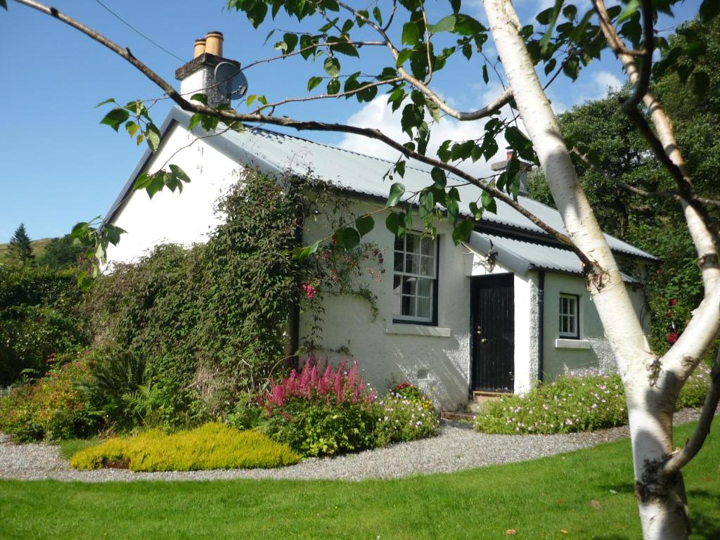 a white house with flowers in front of it at Laich Cottage in Appin