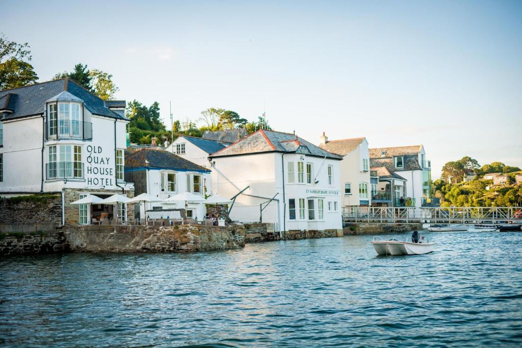 a small boat in the water in front of buildings at The Old Quay House Hotel in Fowey