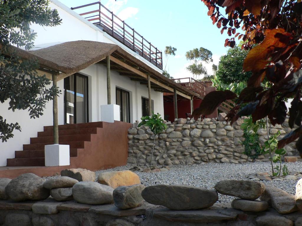 a house with a stone wall in front of it at Mountain View Eco Lodge Montagu in Montagu