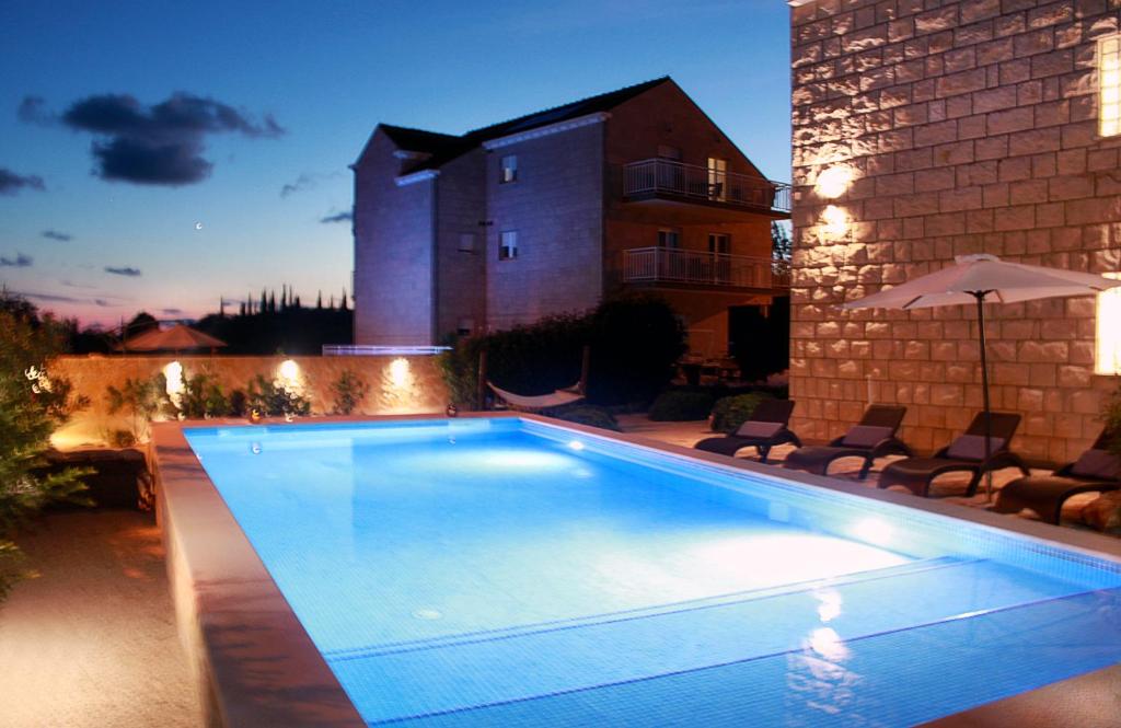 a swimming pool in a yard with chairs and an umbrella at Villa Grand Pinea in Čilipi