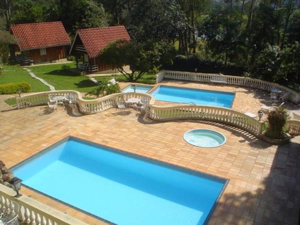 two large blue swimming pools on a brick patio at Pousada Casa Amarela in Piracaia