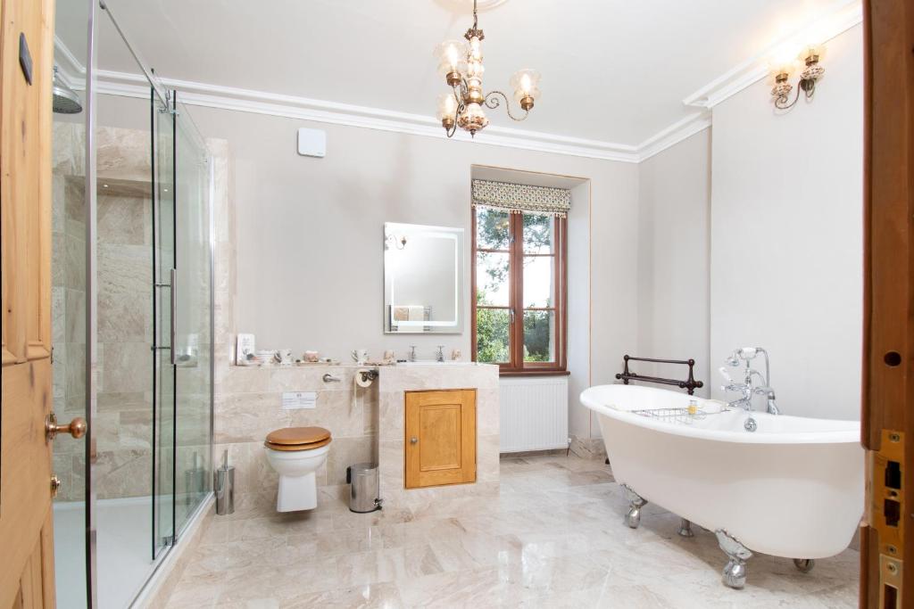 ein Badezimmer mit Badewanne, Toilette und Waschbecken in der Unterkunft Taldraeth - Old Vicarage Guest House in Penrhyndeudreath