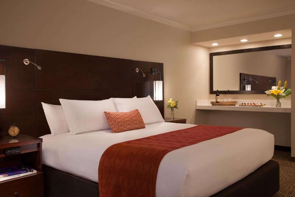 a bedroom with a large white bed with a large mirror at The Lakefront Anchorage in Anchorage