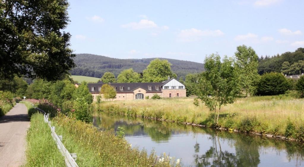 a house in a field next to a river at Malteser Kommende in Engelskirchen