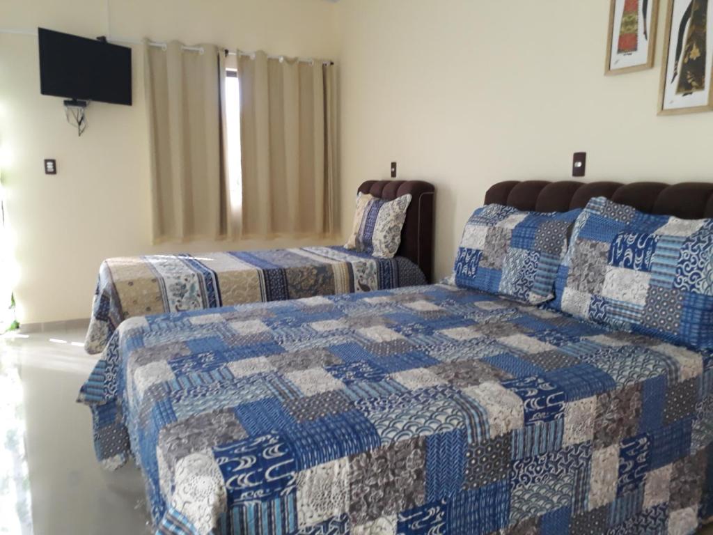 um quarto com 2 camas com colchas azuis e brancas em Suites Flor de Lis em Pirenópolis