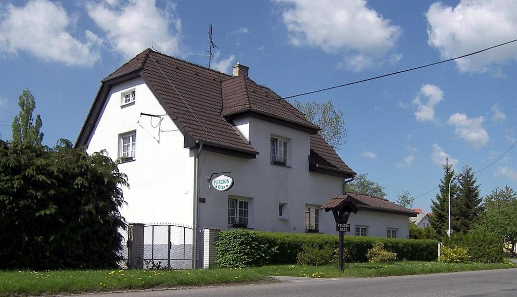 a white house with a clock on the side of it at Penzion Olga in Mariánské Lázně
