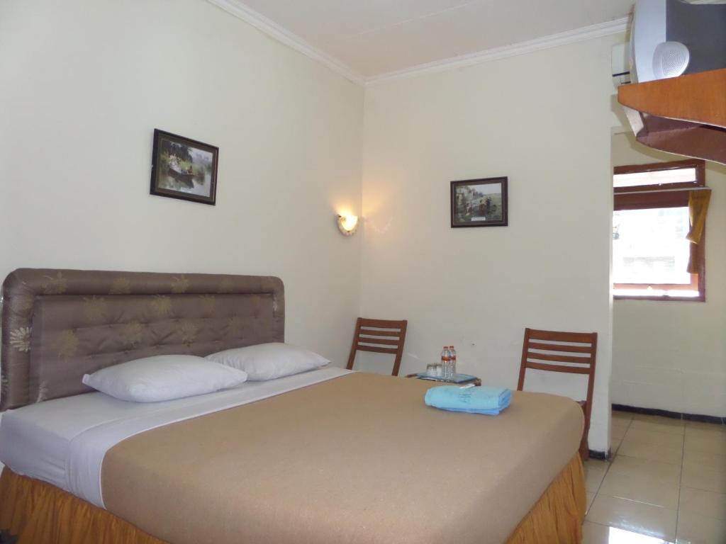 een slaapkamer met een bed met 2 stoelen en een tafel bij Armi Hotel Malang in Malang