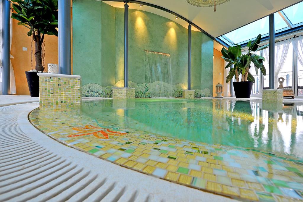 a swimming pool with a mosaic floor in a building at Boutiquehotel La Casa in Tübingen