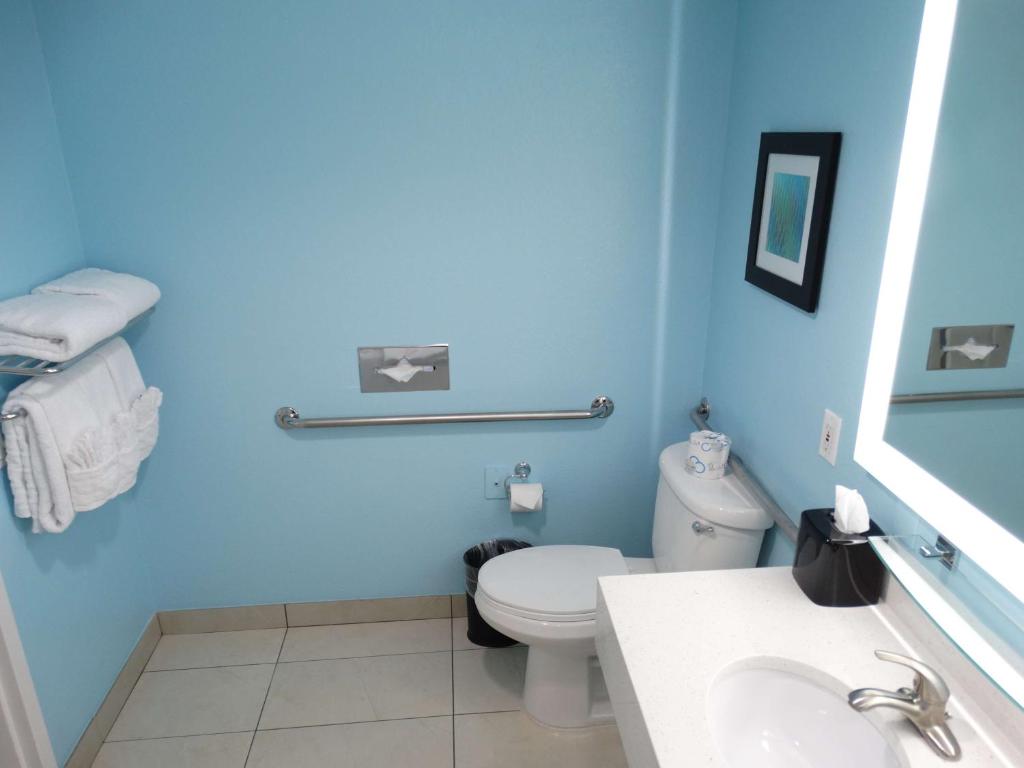 a blue bathroom with a toilet and a sink at Best Western Plus Orlando Lake Buena Vista South Inn & Suites in Kissimmee