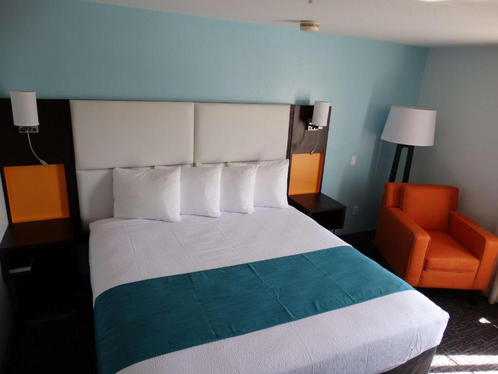 a bedroom with a bed and an orange chair at Best Western Plus Orlando Lake Buena Vista South Inn & Suites in Kissimmee
