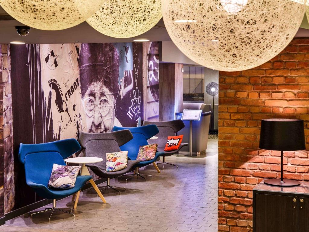 a lobby with chairs and a wall with a mural at ibis London City - Shoreditch in London
