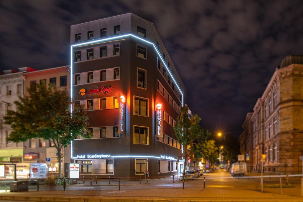 ein Gebäude mit Neonlichtern in der Nacht auf einer Straße in der Unterkunft sevenDays Hotel BoardingHouse Mannheim in Mannheim
