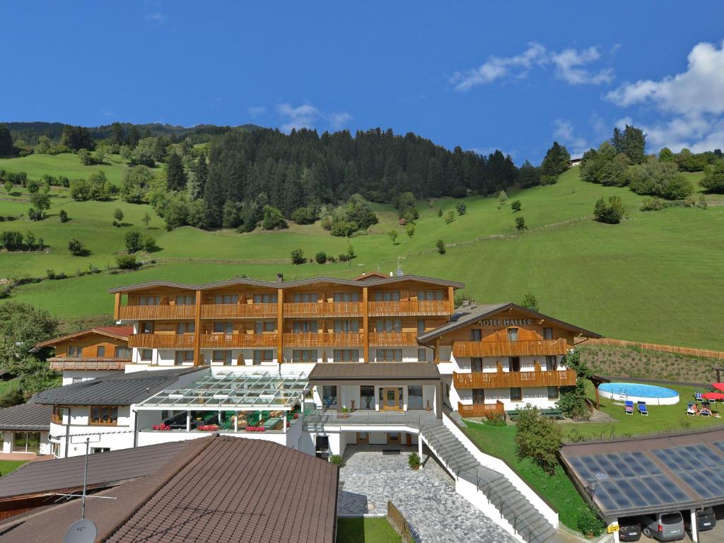 a resort with a large building and a green hill at Naturhotel Haller in Racines
