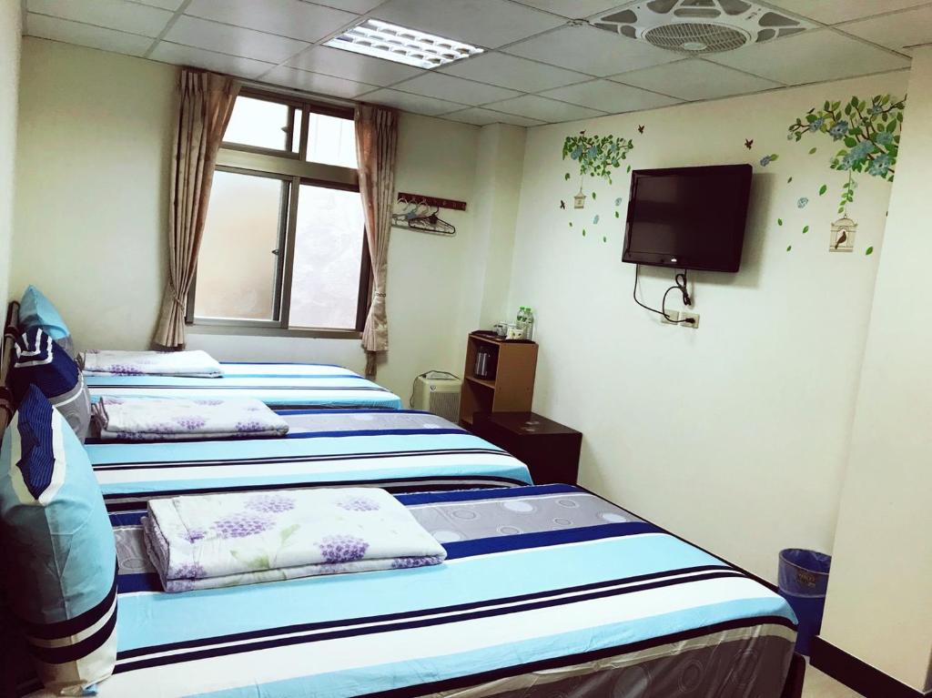 three beds in a room with a tv and a tv at Dongyin First Homestay in Dongyin