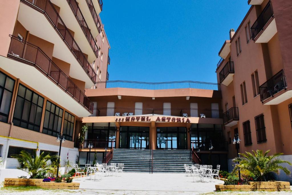 an exterior view of a building with tables and chairs at Hotel Astoria in Pesaro