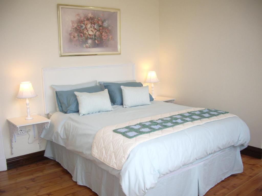 1 dormitorio con 1 cama blanca grande y 2 lámparas en Dee's BnB en Pretoria