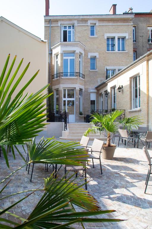 une cour avec des chaises et des arbres ainsi qu'un bâtiment dans l'établissement La Cave de l'Avenue de Champagne, à Épernay