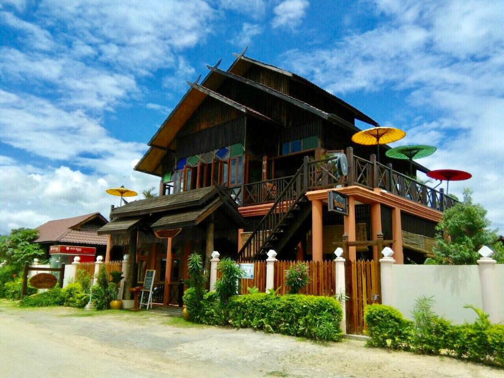 Una gran casa de madera con sombrillas encima. en Inle Cottage Boutique Hotel en Nyaung Shwe