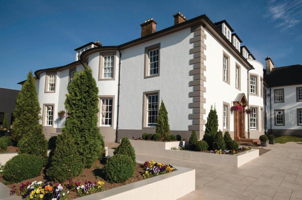 a large white house with a garden in front of it at Hetland Hall Hotel in Dumfries