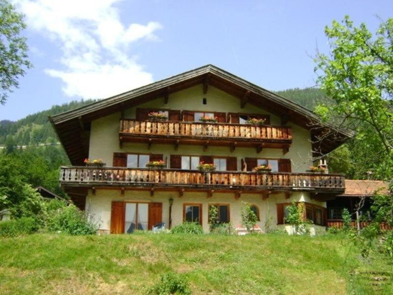 a large house with a balcony on top of a hill at Ferienwohnung Haus Oberlarchhof in Bayrischzell