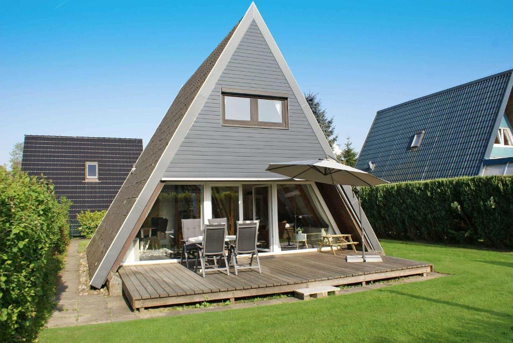 a house with a triangular roof with a deck and an umbrella at Zeltdachhaus mit W_LAN _ Parkplatz in Damp